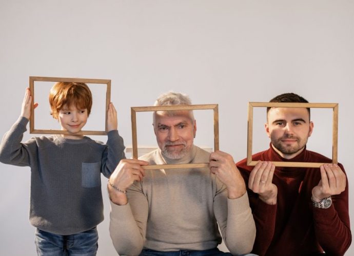 A joyful three generations portrait featuring grandfather, father, and son holding wooden frames indoors.