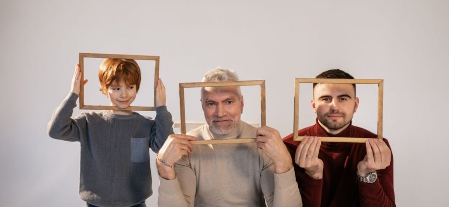 A joyful three generations portrait featuring grandfather, father, and son holding wooden frames indoors.