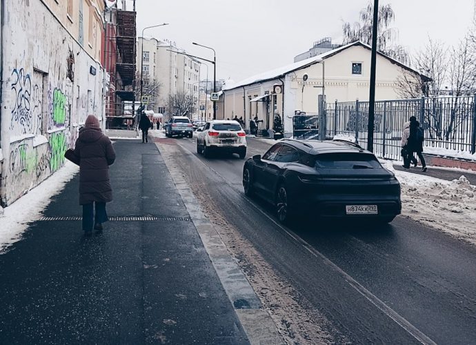 Cars on a snowy street with buildings and people