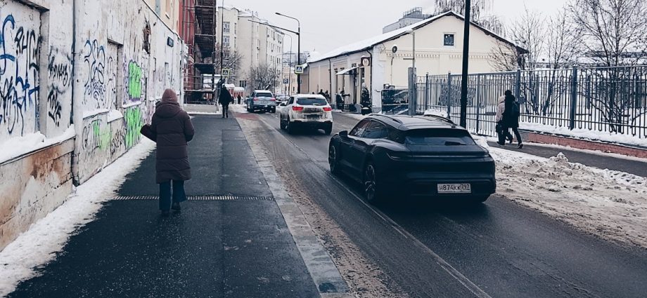 Cars on a snowy street with buildings and people